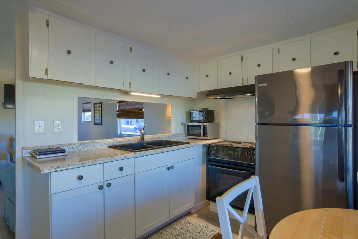 This kitchen interior highlights stainless steel appliances, wooden cabinetry, and a granite countertop, suggesting a practical yet stylish space for cooking. The setup is equipped for preparing home-cooked meals, reflecting the section's mention of simplicity and togetherness in the kitchen.
