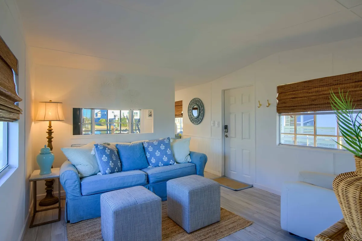 A cozy living room scene with a comfortable sofa, a lamp casting warm light, a decorative mirror, and a coffee table. While focused on interior comfort, the arrangement suggests a welcoming space to unwind after outdoor adventures or relax with a pet after a walk.