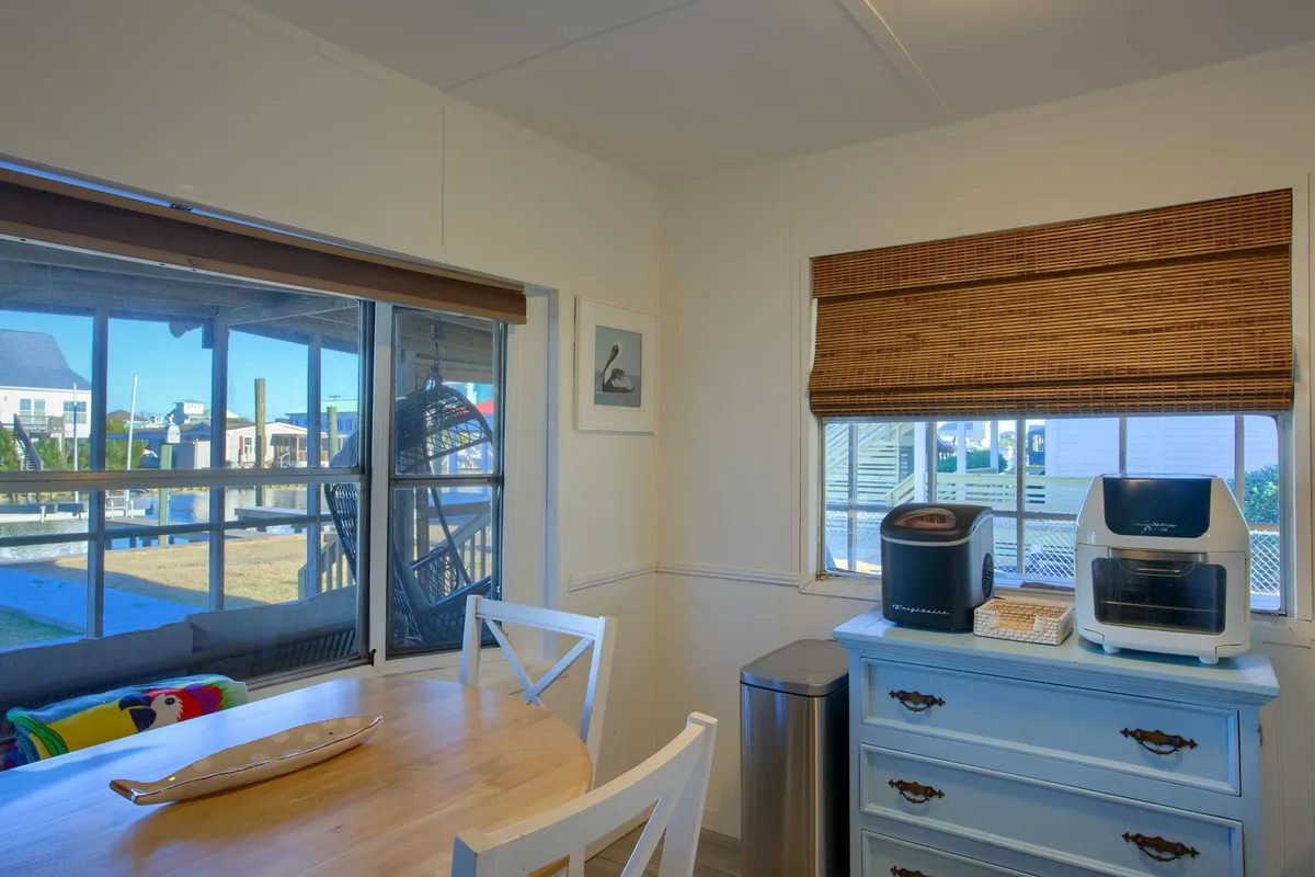 A relaxed and welcoming dining space with a wooden table and blue dresser, featuring a window that provides a glimpse of the outdoors. The natural light and casual setup evoke a sense of gathering before or after a day of exploring local cuisine and attractions.